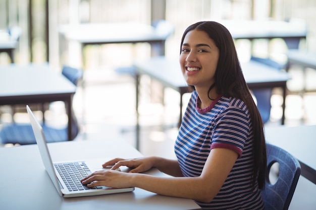 Portrait of schoolgirl using laptop in classroom