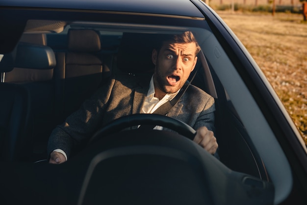 Portrait of a screaming businessman nearly crashing car