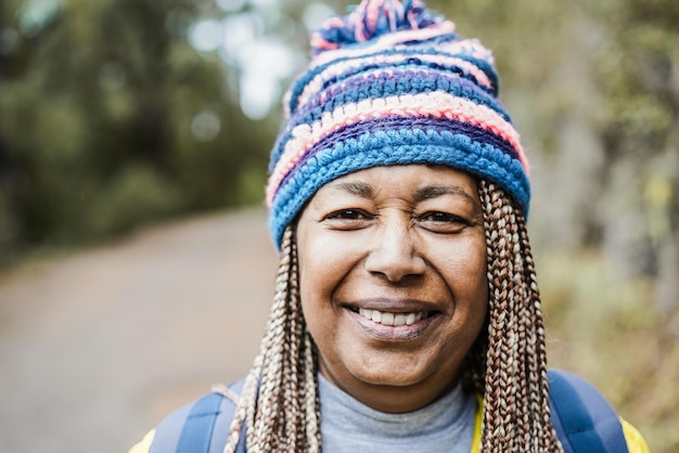 Portrait of senior african woman having fun during trekking day in mountain forest  Focus on face