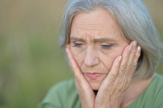 Portrait of senior beautiful sad woman posing outdoors