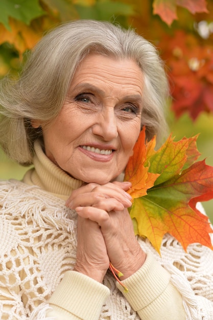 Portrait of senior beautiful woman holding autumn leaves