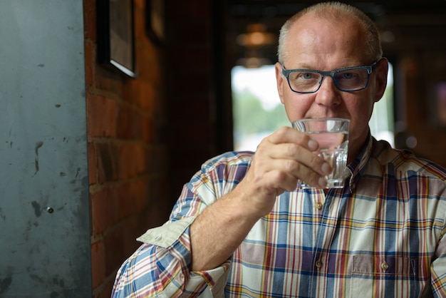 Portrait of senior businessman drinking water at the coffee shop