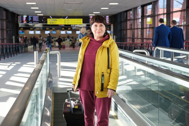 Photo portrait of an senior citizen woman with a suitcaseat the airport