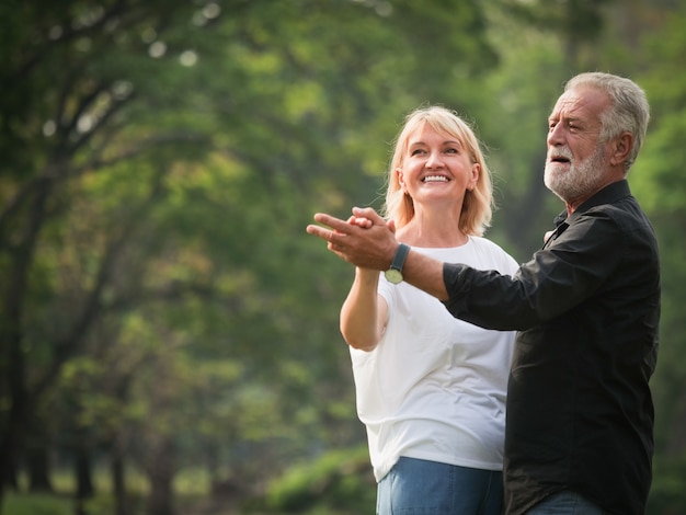 Portrait of Senior couple retirement Man and woman danching  in park together 