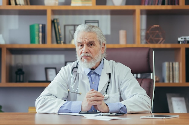 Portrait of a senior experienced doctor grayhaired man working in the office looking at the camera