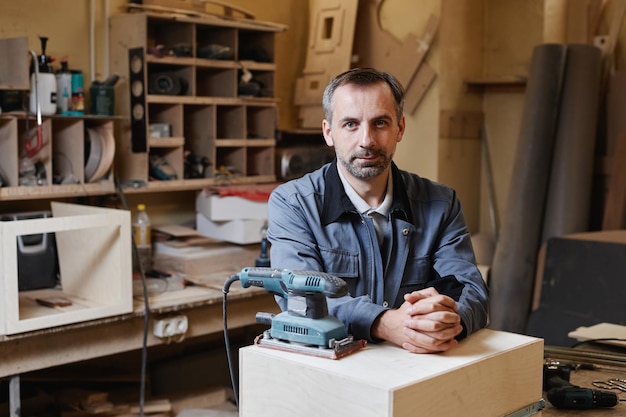 Portrait of senior male worker looking at camera while standing in factory workshop copy space