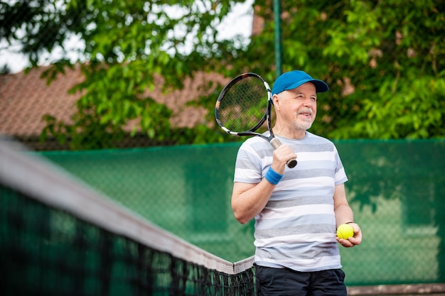 Portrait of senior man playing tennis in an outside, retired sports, sport concept