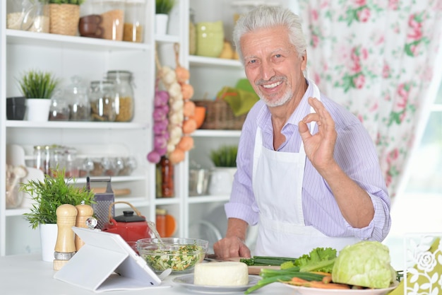 Portrait of senior man preparing dinner in kitchen