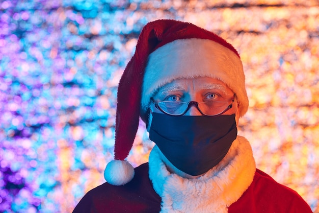 Portrait of senior man in Santa costume wearing protective mask celebrating New Year during pandemic