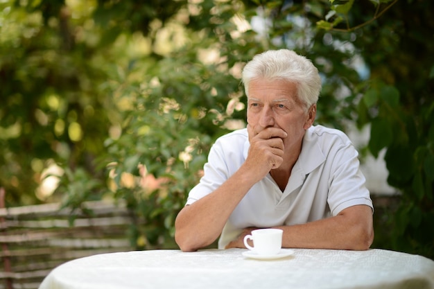 Portrait of a senior man sitting outside with cup