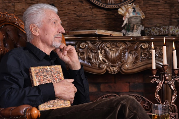 Photo portrait of senior man with book at home