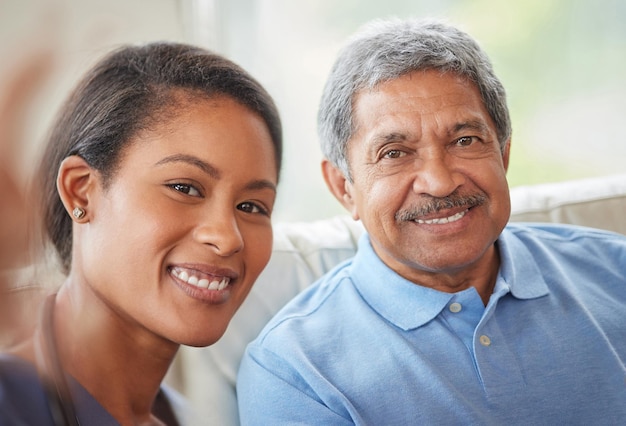 Portrait senior man and woman nurse with a selfie in the living room of a retirement home Healthcare worker and elderly male smile while bonding on a couch together at a house for retired people