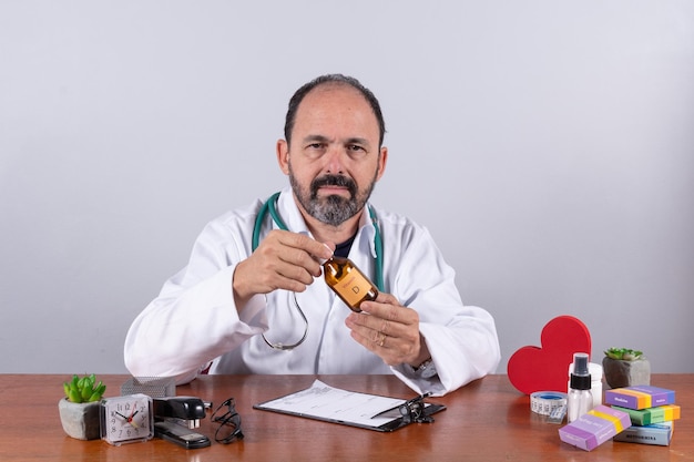 Portrait of senior mature doctor pleasant professional in white coat sitting at table