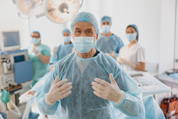 Portrait of senior surgeon standing in operating room ready to work on patient