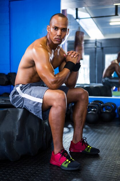 Portrait of serious athlete sitting on tire