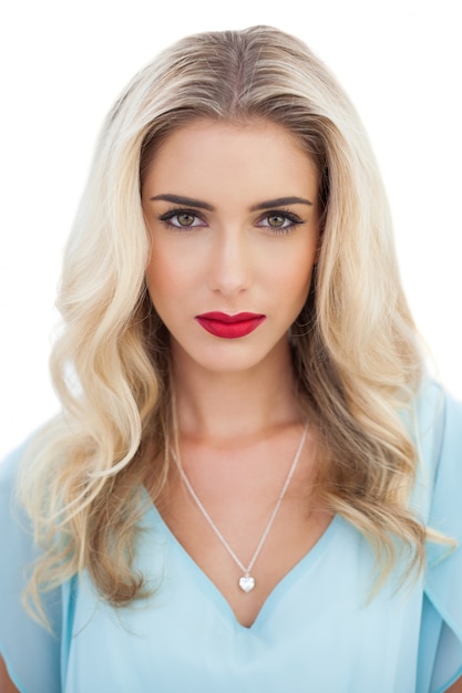 Portrait of a serious blonde woman in blue dress looking at camera