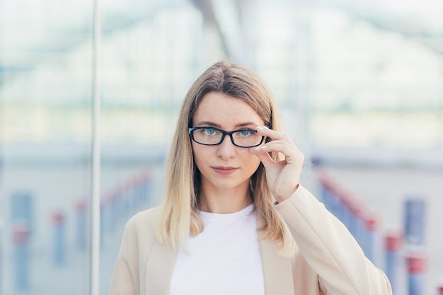 Portrait of a serious business woman, wearing blonde glasses looking at the camera