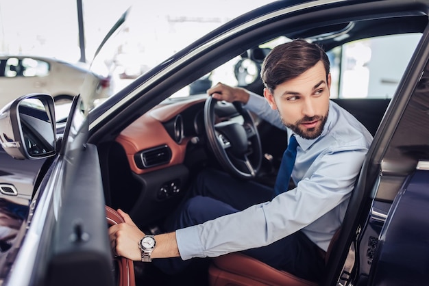 Portrait of serious businessman closing the driver's door of the car