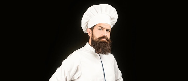 Portrait of a serious chef cook Chef cooks or baker Bearded male chefs isolated on black Cook hat Serious cook in white uniform chef hat