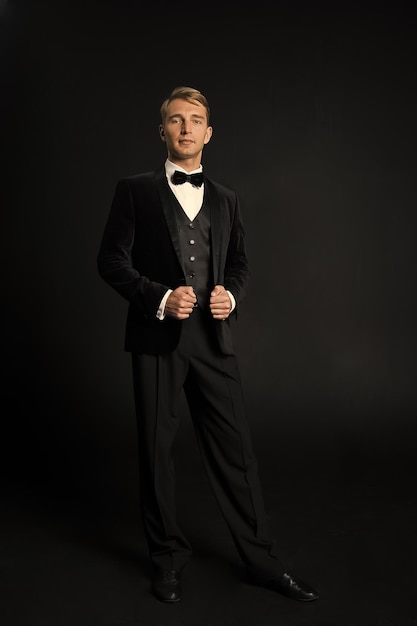 Portrait of serious fashionable handsome man in black tuxedo suit