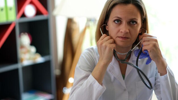 Portrait of serious female doctor posing in clinic office with stethoscope practitioner looking