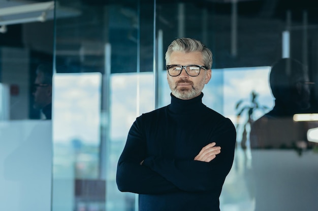 Portrait of serious and focused businessman with crossed arms man working in office wearing glasses