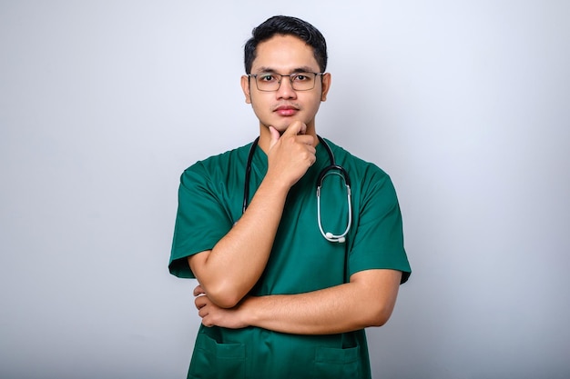 Portrait of a serious male doctor wearing green scrubs with hand on chin