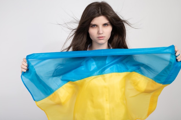 Portrait of serious ukrainian woman with blue and yellow ukrainian flag on a white background