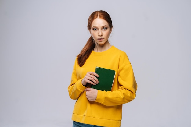 Portrait of serious young woman college student holding books and looking at camera