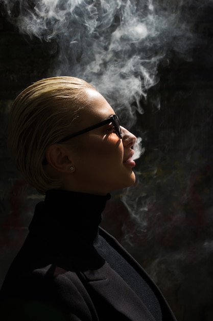 Photo portrait of a sexy blonde who smokes and releases smoke