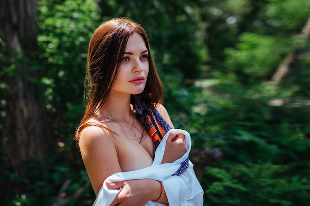 Portrait of a sexy brunette in the park in a white shirt. close-up.