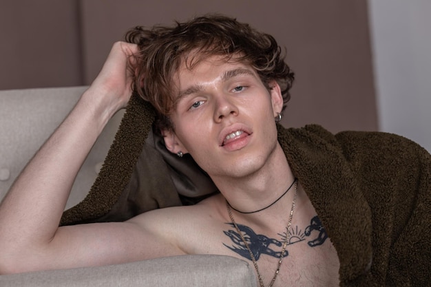 Portrait of a sexy young man leaning on the sofa and covering in warm clothes