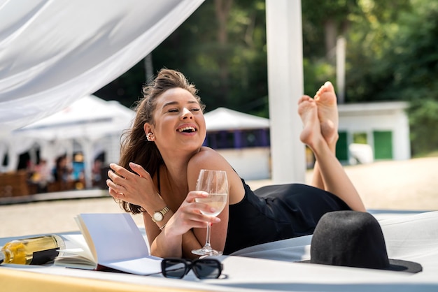 Portrait of sexy young woman wear black dress lying white beds gazebo near beach