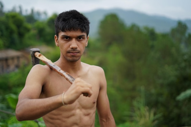 Photo portrait of shirtless young man holding axe standing outdoors