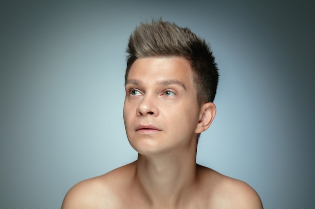 Portrait of shirtless young man isolated on grey wall