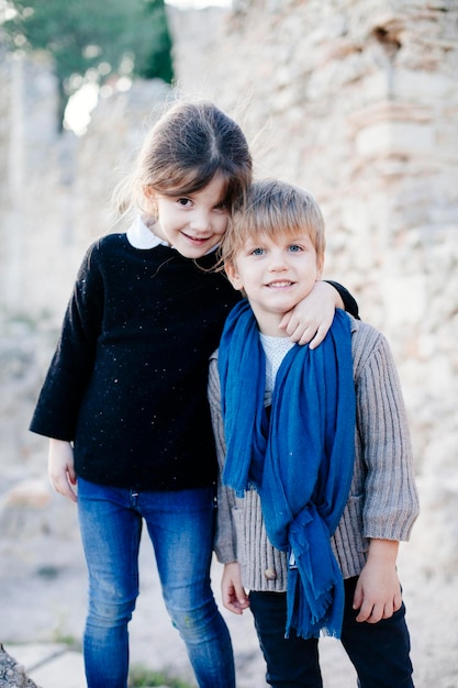 Photo portrait of siblings standing against stone wall