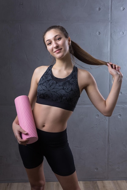 Portrait of a slender athletic young girl against a concrete wall in a fashionable apartment interior