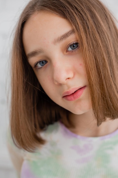 Portrait of a slender teenage girl in a light turtleneck in natural light against a white brick wall. natural beauty, no makeup. problematic skin. space for text. High quality photo