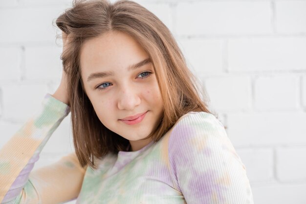 Portrait of a slender teenage girl in a light turtleneck in natural light against a white brick wall. natural beauty, no makeup. problematic skin. space for text. High quality photo