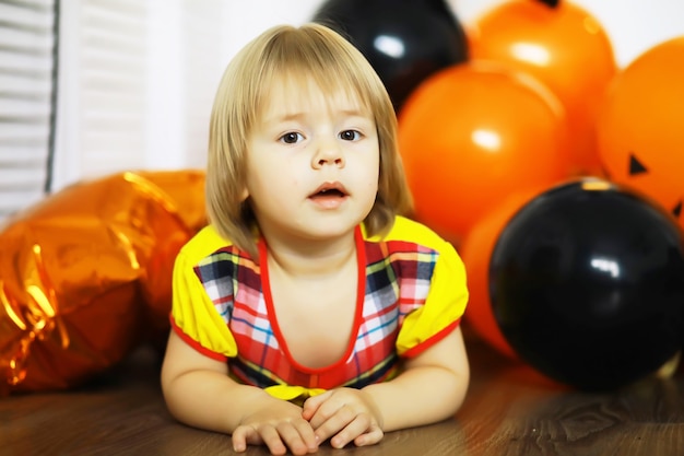 Portrait of a small child lying on the floor in a room decorated with balloons. Happy childhood concept.