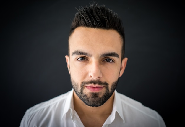 Portrait of a smart serious young man standing against blue background