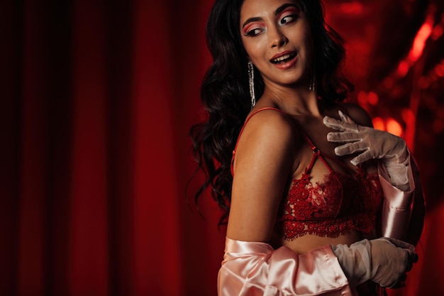 Portrait of smile sexy asian girl glam makeup in lingerie and lace gloves among red shiny balloons