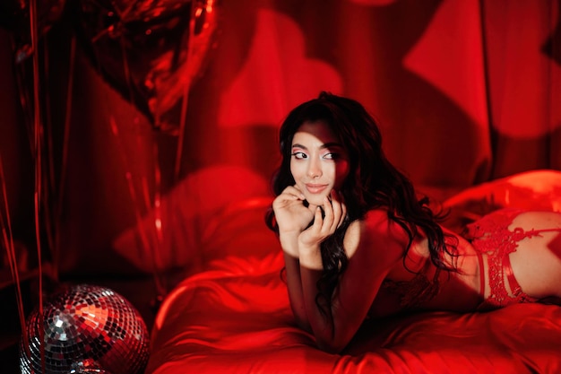 Portrait of smile sexy asian girl glam makeup in red lace lingerie lying on bed at valentines day