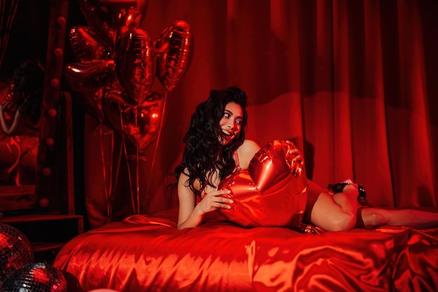 Portrait of smile sexy asian girl glam makeup in red lace lingerie lying on bed at valentines day