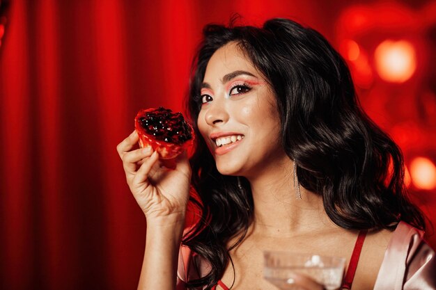 Portrait of smile sexy asian girl glam makeup in red lingerie with cupcake and glass of champagne