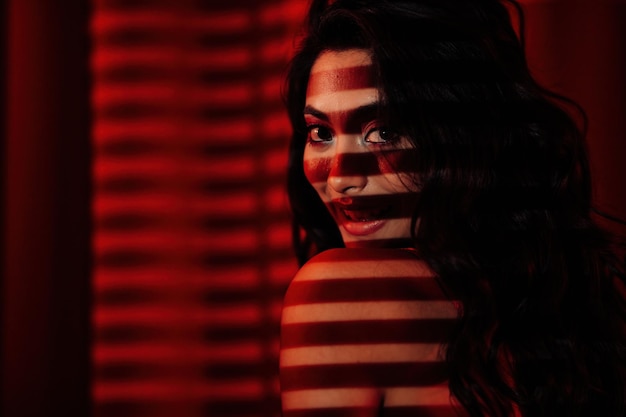 Portrait of smile sexy asian girl glam makeup in red lingerie with light shadow of blinds on skin