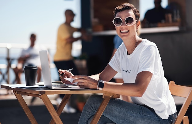 Portrait smile and woman with laptop outdoor and cafe in morning for scriptwriter with sunglasses Summer cheerful and happy with computer coffee and paper for inspiration web and creative