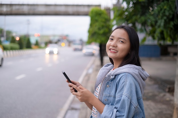 Portrait smile young girl use mobile phone on road background.