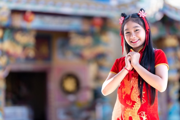 Portrait smiles Cute little Asian girl wearing red cheongsam dress traditional decoration for Chinese new year festival celebrate culture of china at Chinese shrine