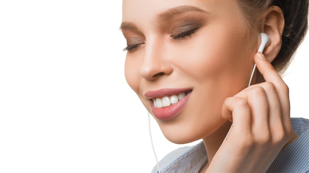 Portrait of a smiley young woman listening to the music via earphones